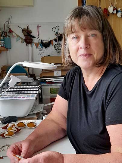 Alison from Flora patterns sitting at her work table in her studio